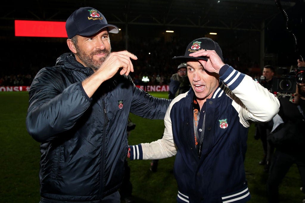 Ryan Reynolds e Rob McElhenney celebrando com jogadores do Wrexham AFC