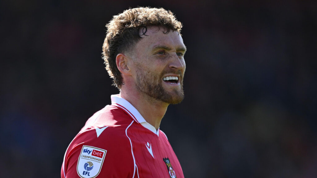 Dan Scarr sorrindo com a camisa do Wrexham
